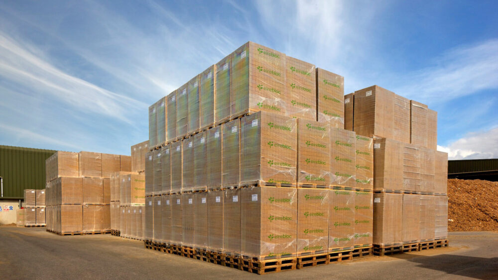 A large stack of wrapped Eirebloc pallet-block bundles in the factory yard.
