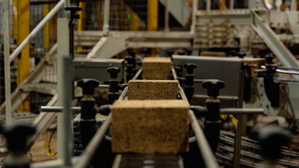 A composite pallet block moving between guide rollers on the production line.