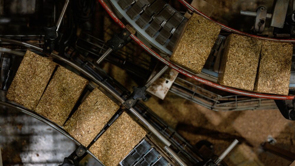 Composite pallet blocks travelling along a curved overhead conveyor.