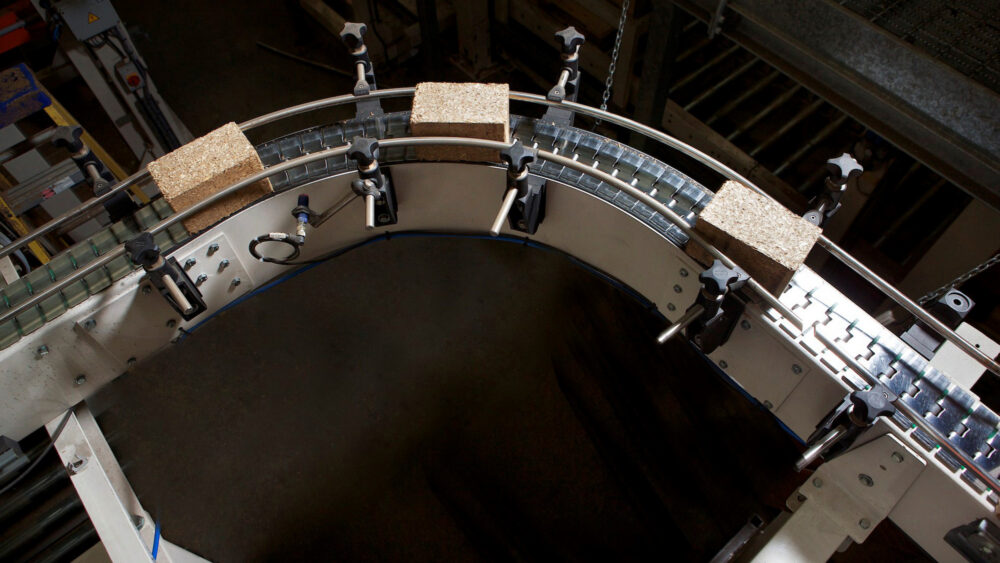 Three composite pallet blocks rounding a curved conveyor in the Eirebloc plant, seen from above.