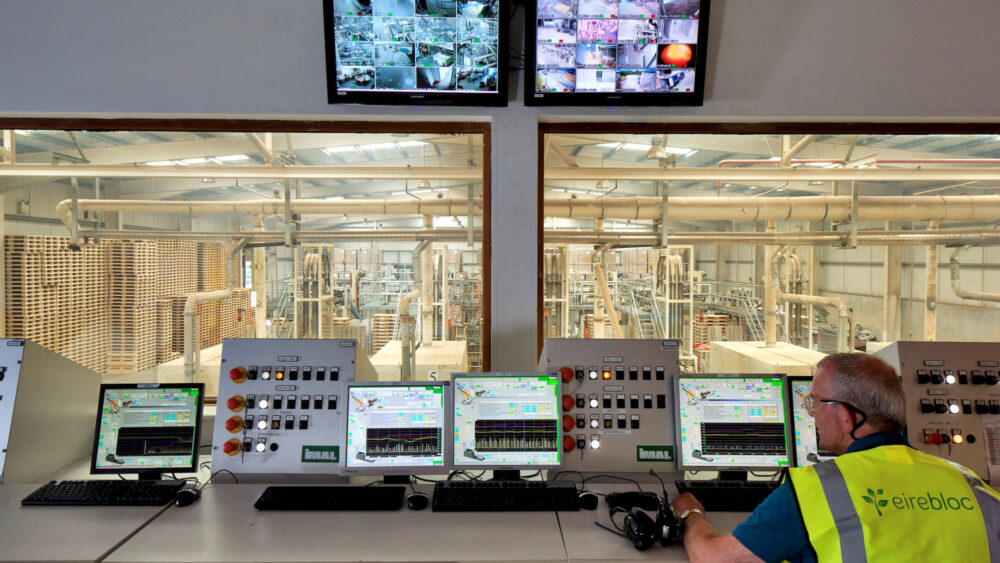 An Eirebloc operator at the control desk, with CCTV screens and a window overlooking the plant.
