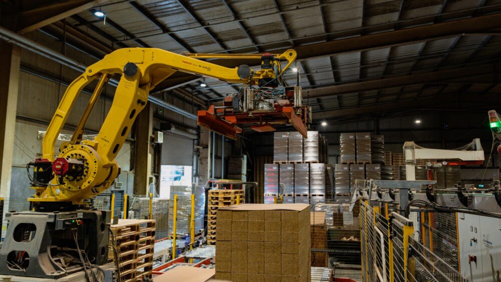 A robotic arm stacking finished composite blocks in the Eirebloc packing hall.
